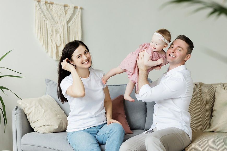 Frau, Mann und Kind auf dem Sofa, alle lächeln