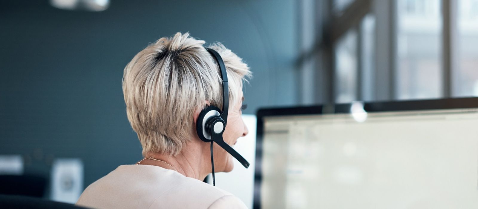 Frau mit Headset am Computer/Bildschirm