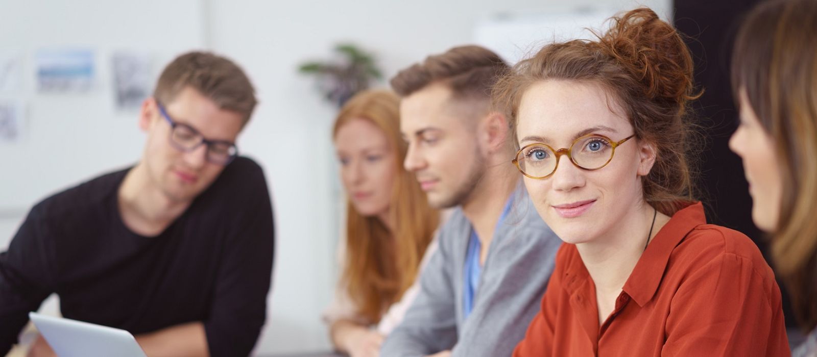 Drei Frauen, zwei Männer an Tischen in einer Weiterbildungssituation