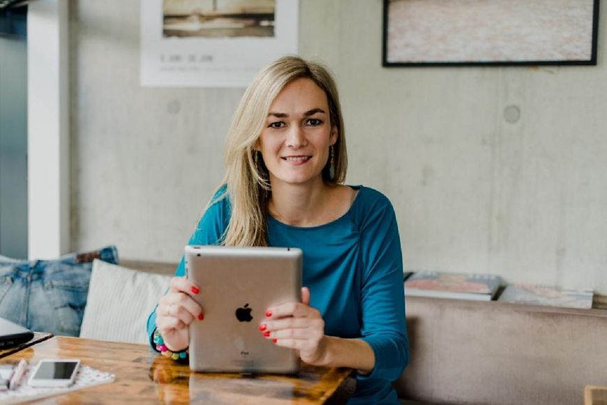 Dominika Rotthaler am Schreibtisch mit Tablet in den Händen