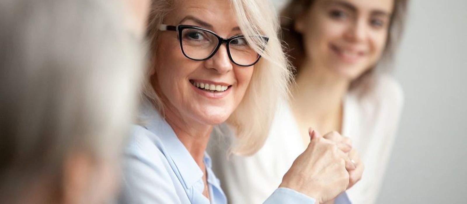 Eine Frau mit Brille im Gespräch mit drei weiteren Menschen, alle sitzen an einem Tisch