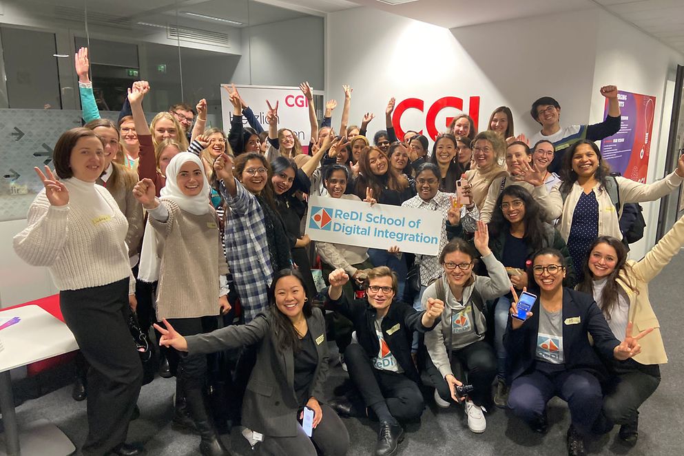 Gruppenfoto mit vielen jungen Leuten, die in ihrer Mitte das Schild "ReDI School of Digital Integration" halten