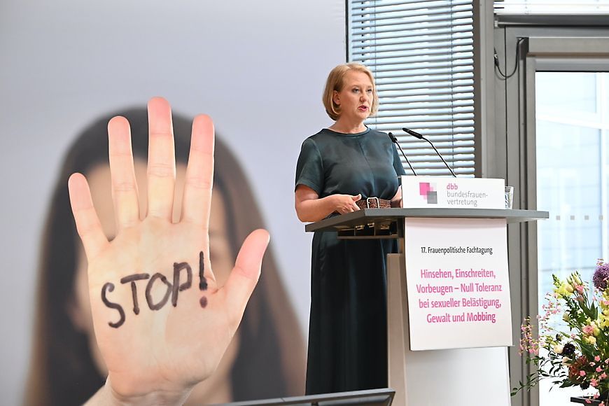 Bundesministerin Lisa Paus steht am Redepult, im Hintergrund eine Hand, auf der Stop steht. 