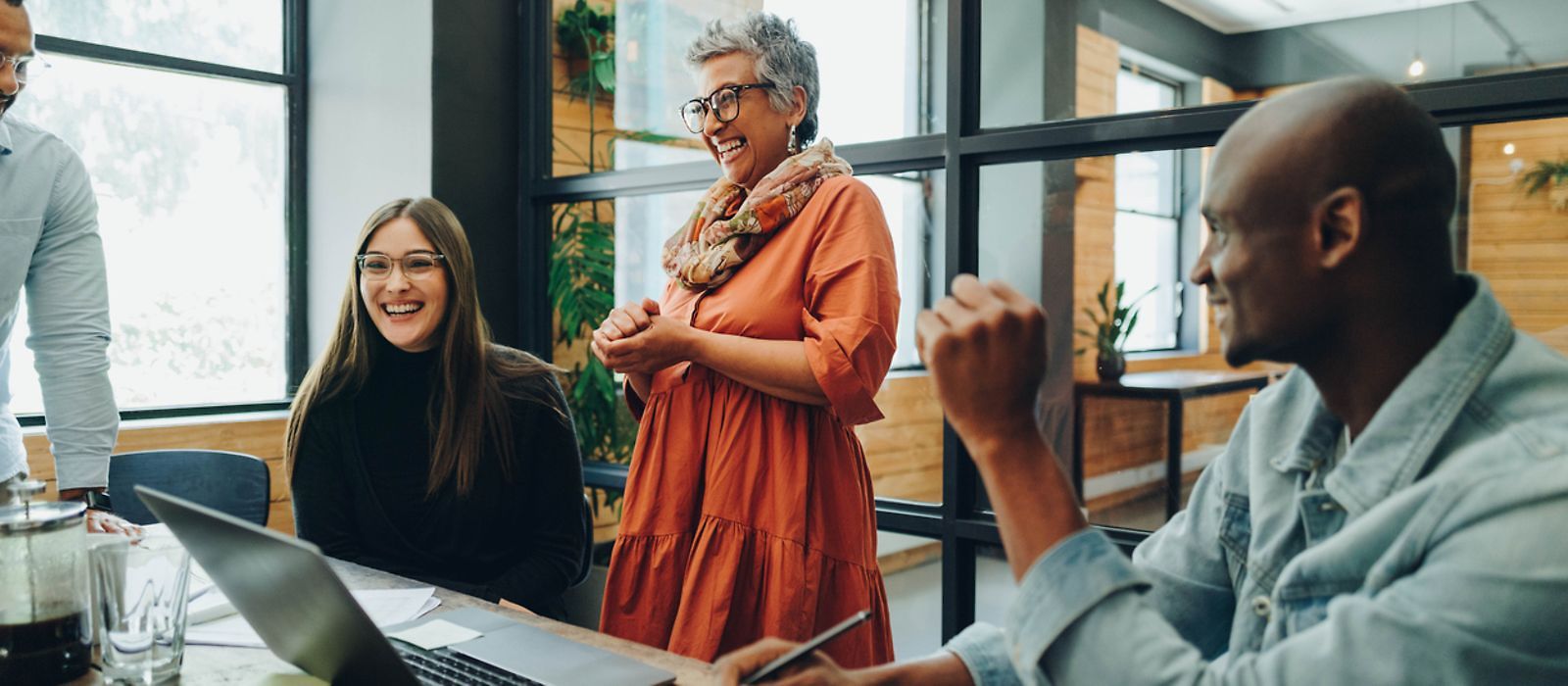 Diverse Personen im Arbeitskontext lachen zusammen 