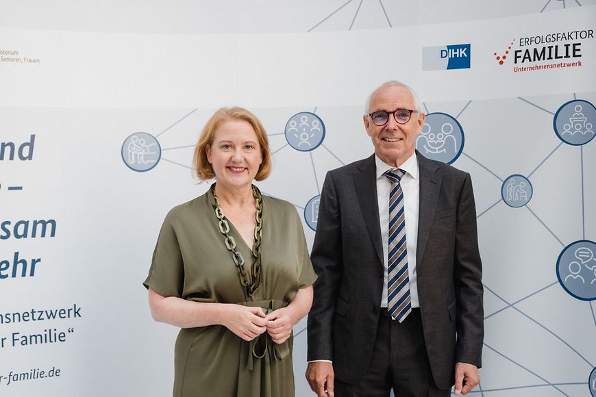 Die Bundesfamilienministerin Lisa Paus steht mit dem DIHK-Präsidenten Peter Adrian vor einer Plakatwand.